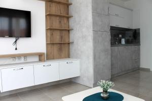a kitchen with white cabinets and a flat screen tv at Horizon Katrina Apartments - Sea line & Beach Access in Sveti Vlas
