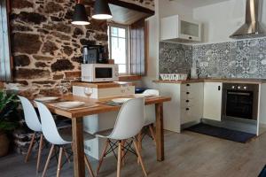 cocina con mesa de madera y sillas blancas en My Historic House 2, en Bragança