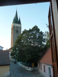 una torre del reloj alta con un árbol en una calle en Apartmán Horní Brána, en Telč