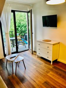 a room with a dresser and a tv and a chair at Apartament z balkonem blisko plaży in Niechorze