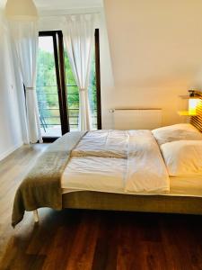 a bedroom with a large bed with a large window at Apartament z balkonem blisko plaży in Niechorze