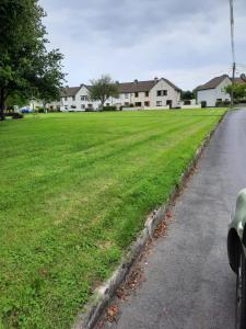 a field of green grass next to a road at Lovely ballina townhouse in Ballina