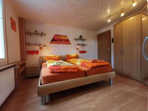 ein Schlafzimmer mit einem großen Bett mit orangefarbener Bettwäsche in der Unterkunft Ferienwohnungen im Fürstenland in Gossau SG