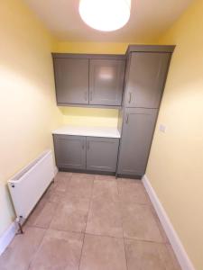 an empty kitchen with gray cabinets and a tile floor at Lovely ballina townhouse in Ballina