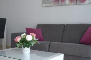 a vase of flowers on a table in front of a couch at Albur Village in Alvor