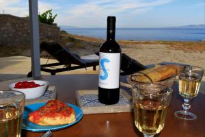 a bottle of wine sitting on a table with glasses at Aegean Blue Houses in Mandrakia