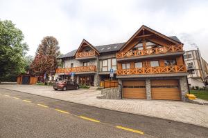 a large house with a car parked in front of it at Apartment Tiliana in Vysoke Tatry - Tatranska Lomnica.