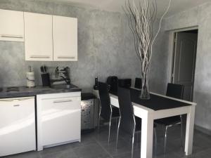 a kitchen with white cabinets and a table with chairs at Piscine ET JACUZZI ST GEORGES DE DIDONNE a 1km de la plage in Saint-Georges-de-Didonne