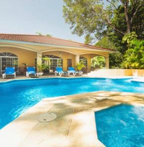 una piscina con sillas azules y una casa en The Amazing Hispaniola Villa 145 en Sosúa