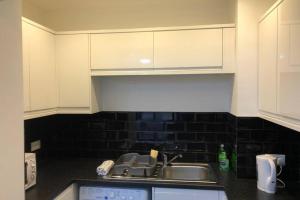 a kitchen with white cabinets and a sink at Fishergate ApartHotel 1 - Stylish City Centre Apartment in Preston