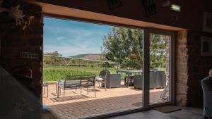 una puerta corredera de cristal que da a un patio con mesa y sillas en Quinta Ponte da Capinha, en Capinha