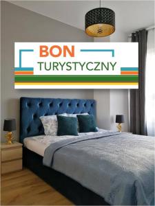 - une chambre avec un lit et un panneau qui lit bon tuminyasy dans l'établissement MA Sea Apartments - Baltica Towers, à Gdańsk