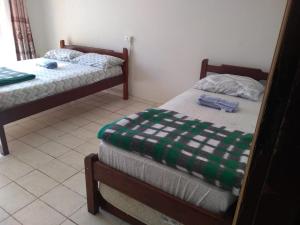 two beds in a room with a green and white blanket at Santo Ivo in Aparecida