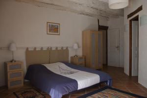 - une chambre dotée d'un lit avec une couverture bleue et blanche dans l'établissement les Tours de Bombel, à Saint-Amand-de-Coly