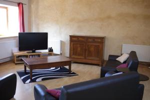 - un salon avec une télévision, une table et des chaises dans l'établissement les Tours de Bombel, à Saint-Amand-de-Coly
