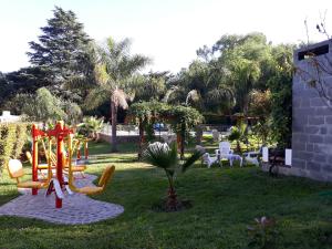 einen Spielplatz in einem Garten mit Stühlen und Bäumen in der Unterkunft Candy Apart Hotel in Villa General Belgrano