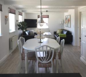 a dining room and living room with a white table and chairs at Lejlighed ved Kongeåen in Ribe
