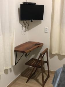 uma mesa de madeira com uma cadeira e uma televisão na parede em Casa de São Jorge em Pirenópolis