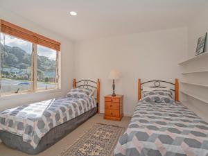 twee bedden in een witte kamer met een raam bij Tairua Waterfront Retreat - Tairua Apartment in Tairua