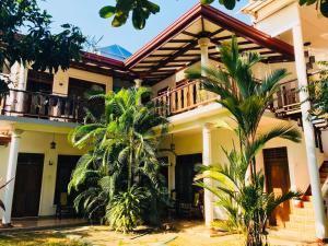 a house with palm trees in front of it at Mermaid Inn in Mirissa