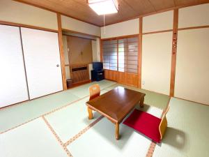 Habitación con mesa de madera y silla en Yufuin Onsen Hasuwa Inn, en Yufu