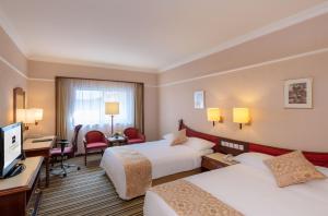 um quarto de hotel com duas camas e uma televisão em Metropark Lido Hotel Beijing em Pequim