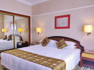 una habitación de hotel con una cama grande con sábanas blancas en Metropark Lido Hotel Beijing en Pekín