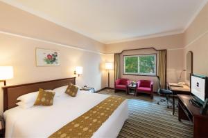 北京市にあるメトロパーク リド ホテル ベイジンのベッド、デスク、テレビが備わるホテルルームです。