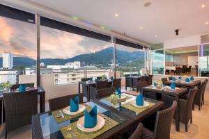 Un restaurante con mesas y sillas y grandes ventanales. en Grand Sunset Hotel Phuket, en Karon Beach
