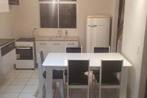uma cozinha branca com uma mesa e cadeiras brancas em Apto 2 quartos São José dos Pinhais Curitiba sem taxa de limpeza e próximo do aeroporto em São José dos Pinhais