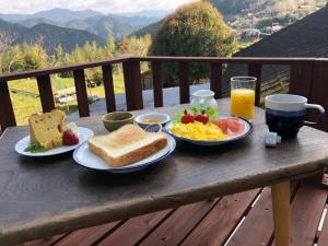 una mesa de desayuno con productos para el desayuno y un vaso de zumo de naranja en 旅籠まさら HATAGO MaSaRa en Tanabe