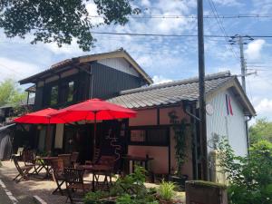 un restaurante con mesas y sombrillas rojas delante de él en 旅籠まさら HATAGO MaSaRa en Tanabe