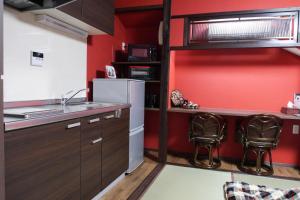 a kitchen with red walls and a sink and two chairs at Kanazawa Machiya Aburaya in Kanazawa +21 photos