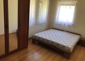 a small bedroom with a bed and a mirror at Panoráma Apartman Ház in Pannonhalma