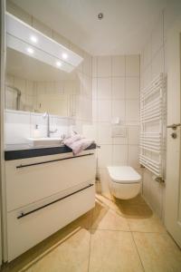 ein weißes Bad mit einem Waschbecken und einem WC in der Unterkunft Südstrandhus Urlaub mit Hund Wohnung 2 unten in Borkum