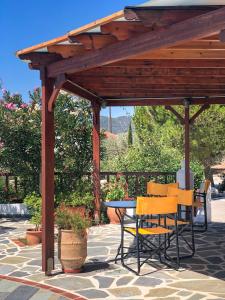 een houten pergola met een tafel en stoelen op een patio bij Pleiades Samos in Marathokampos