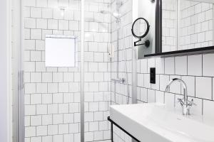 a white tiled bathroom with a sink and a mirror at Winterfeld Guest House Bodenmais in Bodenmais +17 photos