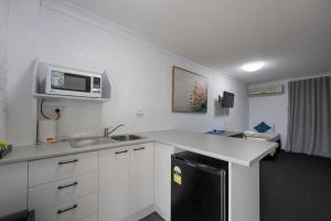 eine Küche mit einer Spüle und einer Mikrowelle in der Unterkunft Bribie Waterways Motel in Bongaree