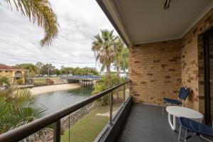 Un balcón con mesa y sillas y un río. en Bribie Waterways Motel, en Bongaree