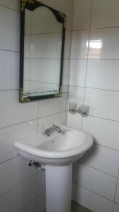 uma casa de banho com um lavatório branco e um espelho. em Jojo's Palace Annex em Gulu