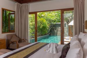 a bedroom with a bed and a view of a pool at KoenoKoeni Villa in Seminyak