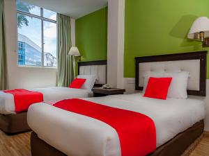 duas camas num quarto de hotel com paredes verdes em Super OYO 90055 Mansion Inn em Sibu