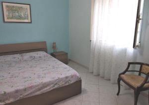 Un dormitorio con una cama y una silla y una ventana. en BaseCamp Ogliastra - Flat Green, en Santa Maria Navarrese