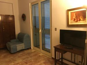 ein Wohnzimmer mit einem TV und einem Stuhl in der Unterkunft Holiday Nizza House in Nizza di Sicilia
