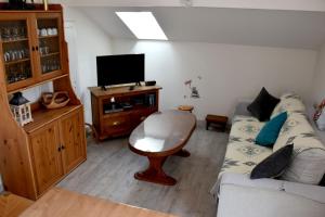 a living room with a couch and a flat screen tv at Gîte 60M2 in Xonrupt-Longemer