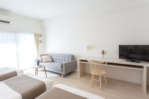 Una sala de estar blanca con un sofá y un televisor. en Nedoco Osaka West, en Osaka