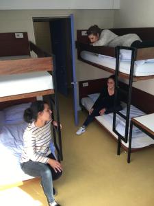 2 personas sentadas en literas en una habitación compartida en Auberge de Jeunesse HI Lorient, en Lorient