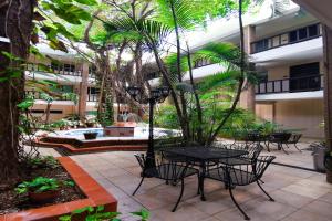 un patio con mesa, sillas y palmeras en Grand Hotel Colonial Cancun, en Cancún