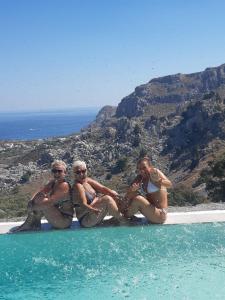 un grupo de mujeres sentadas en el borde de una piscina en Bouganville Bed & Breakfast Stegna en Archangelos