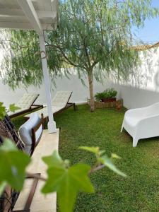 a yard with chairs and an umbrella and a tree at Falso pepe Marzamemi in Marzamemi
